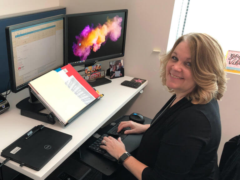 woman smiling up from her desk